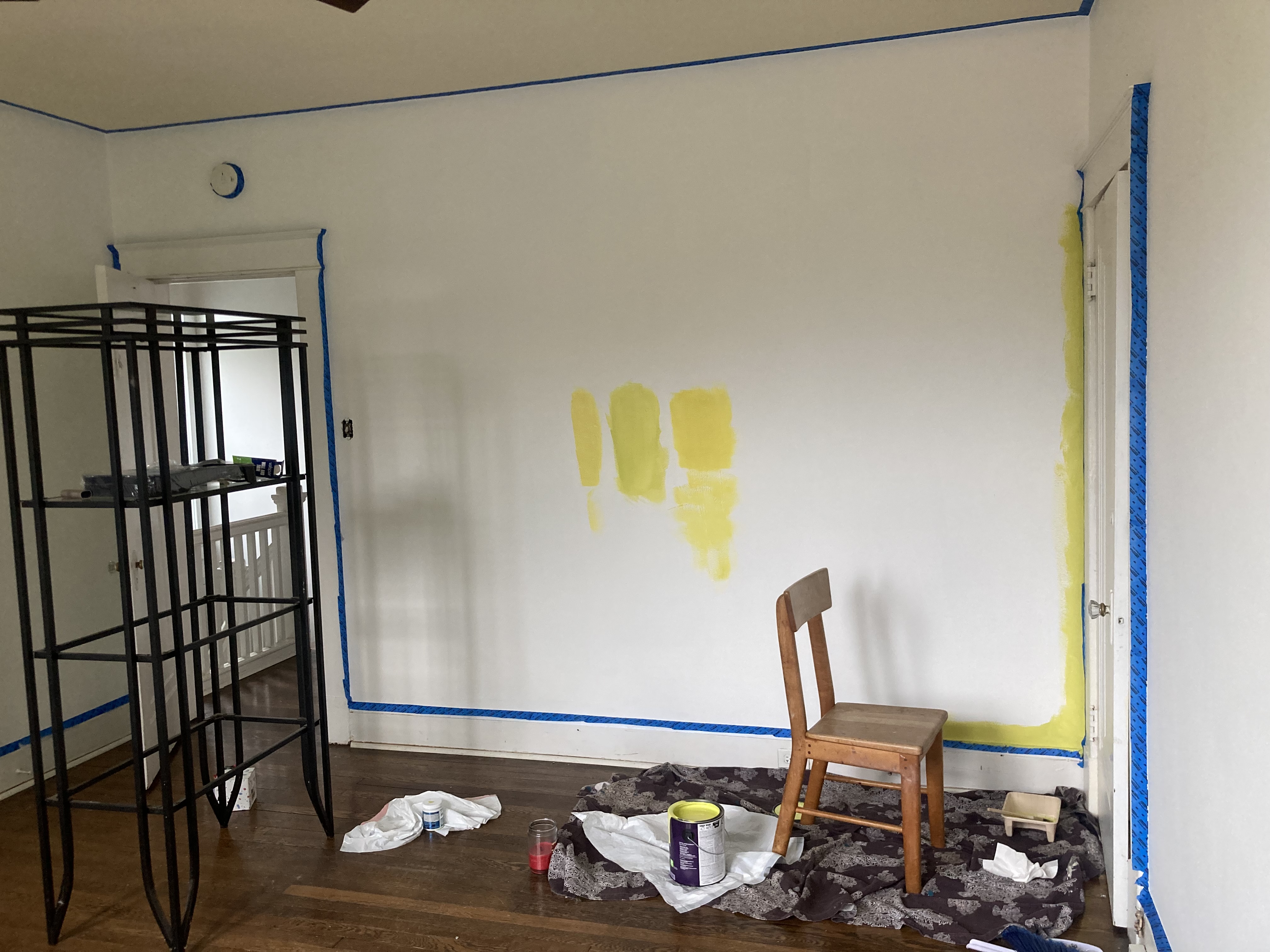 an empty room with a chair and green paint swatches on the wall