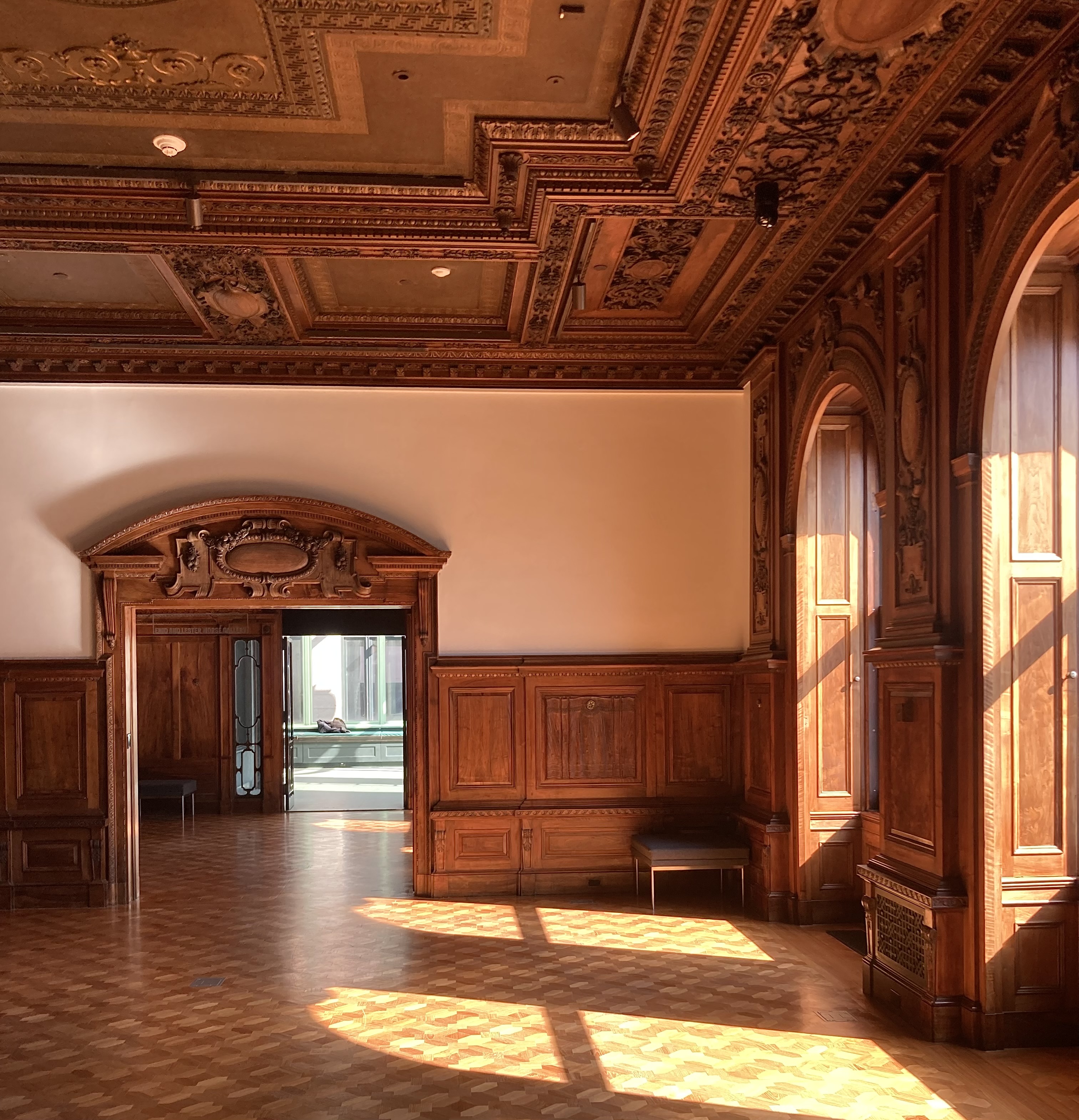 a bright room with dark wood carving and windows to the right