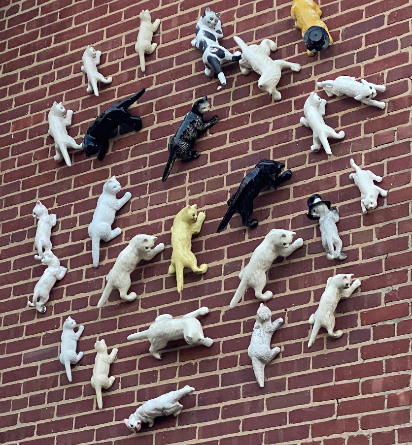 porcelain cats attached to the brick side of a house