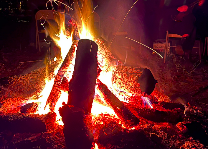 a campfire with a mandolin and folding chairs