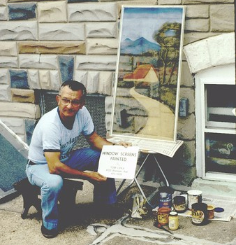 Adult male window screen painter working on the sidewalk
